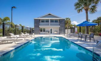 a large swimming pool with lounge chairs and a house in the background , surrounded by palm trees at Legacy Vacation Resorts-Indian Shores