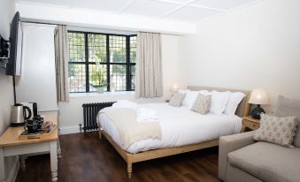 a large bed with white linens is in a room with hardwood floors and a window at The Fox