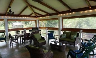 a spacious outdoor space with a wooden roof , multiple couches , chairs , and a dining table at Casa Piedra