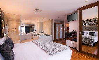 a large bedroom with a king - sized bed , a bathroom with a bathtub , and a television mounted on the wall at The Twelve Hotel