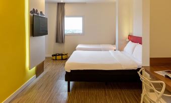 a modern hotel room with wooden flooring , white walls , and two beds with black headboards at Ibis Styles Birigui