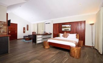a large bed with a wooden headboard is in the middle of a room with a desk and chairs at Aqua Safari Resort