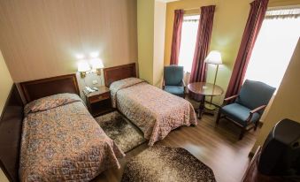 a hotel room with two beds , one on the left and one on the right side of the room at Hotel Regency