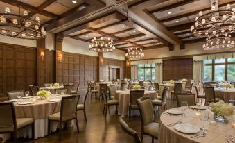 a large dining room with wooden ceiling , chandeliers , and tables set for a formal event at The Sewanee Inn