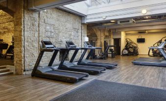 a gym with various exercise equipment , including treadmills and stationary bikes , under a skylight with a stone wall at Mercure Blackburn Dunkenhalgh Hotel & Spa