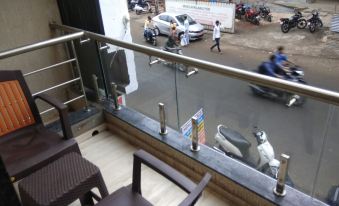 a balcony with a view of the street , people walking on the sidewalk , and vehicles passing by at Hotel Rajlaxmi Grand