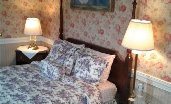 a cozy bedroom with a floral comforter , two lamps on either side of the bed , and a wooden headboard at The Brick Hotel