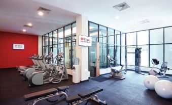 a well - equipped gym with various exercise equipment , including treadmills and weight machines , set up in front of large windows at Hilton Garden Inn Puchong