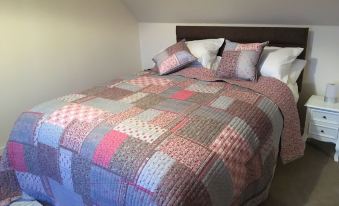 a bed with a colorful quilt and pillows is shown in a room with a slanted ceiling at Hillside