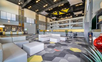 a modern office building with a lobby area , featuring white chairs and a gray carpet at Holiday Inn Morgantown - Reading Area