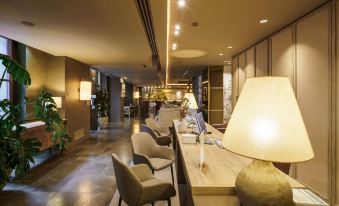 a modern hotel lobby with various seating options , including couches and chairs , as well as a dining table at Barceló Oviedo Cervantes