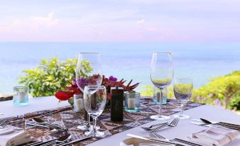 a table is set with wine glasses , wine bottles , and cutlery overlooking the ocean on a balcony at Curacao Marriott Beach Resort