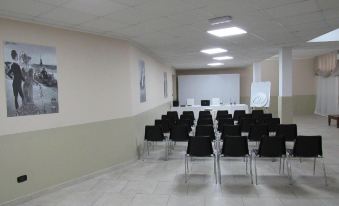a large conference room with rows of black chairs and a whiteboard , ready for an event at Green Hotel