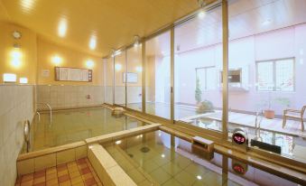 an indoor swimming pool with a sunken hot tub , surrounded by large windows that provide a view of the surrounding area at Hotel WBF Grande Asahikawa（Natural Hot Spring MinaPirika No Yu)
