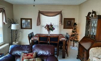 a living room with a couch , dining table , chairs , and a christmas tree in the background at Barclay Bed and Breakfast