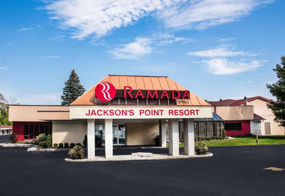 "a large building with a sign that reads "" ramada jackson 's point resort "" prominently displayed on the front" at Ramada by Wyndham Jacksons Point