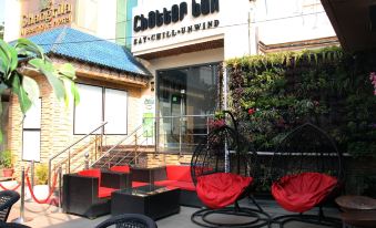 a small restaurant with outdoor seating and a red patio umbrella in front of it at Jalandhar Shangrila Hotel