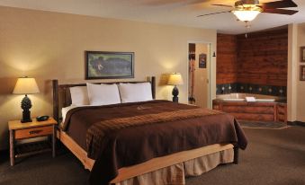 a large bed with a brown blanket and white pillows is in the middle of a room with a wooden headboard , lamps , and a rug at Boarders Inn & Suites by Cobblestone Hotels – Waukon