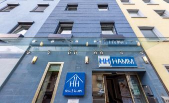 a blue and yellow facade of a hotel , with multiple signs on the building advertising the establishment at Hamm