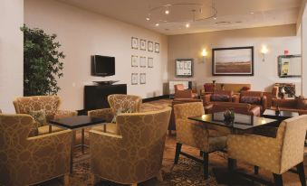 a hotel lobby with various seating options , including couches , chairs , and a television . several people enjoying the space at DoubleTree by Hilton Pittsburgh Monroeville Convention Center