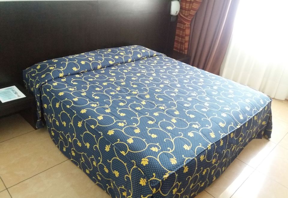 a neatly made bed with a blue and yellow floral patterned sheet is shown in a bedroom at Hotel Panorama