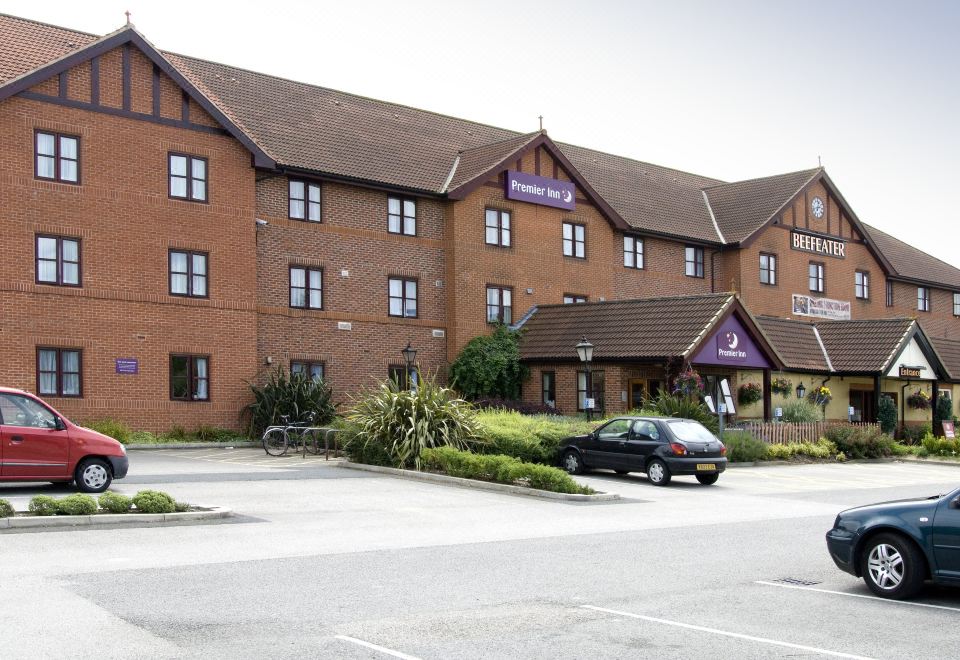 a brick hotel building with a purple sign on the front , surrounded by trees and a parking lot at York North West