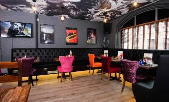 a modern restaurant with black walls , wooden floors , and various dining tables and chairs arranged in a stylish setting at Arthouse Hotel