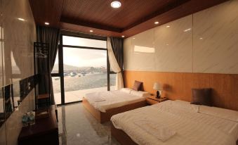 a modern hotel room with two beds , a window offering a view of the ocean , and wooden ceiling panels at The Sea Rock Binh Hung