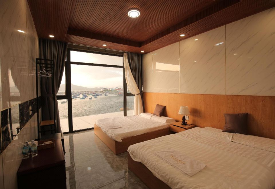 a modern hotel room with two beds , a window offering a view of the ocean , and wooden ceiling panels at The Sea Rock Binh Hung