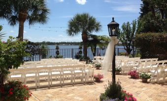 a wedding ceremony is taking place on a patio overlooking a body of water , with white chairs set up for guests at Inn on the Lakes