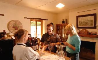 a group of people , including a man and a woman , are standing around a dining table , each holding a glass of wine at Stone Hut Cottage
