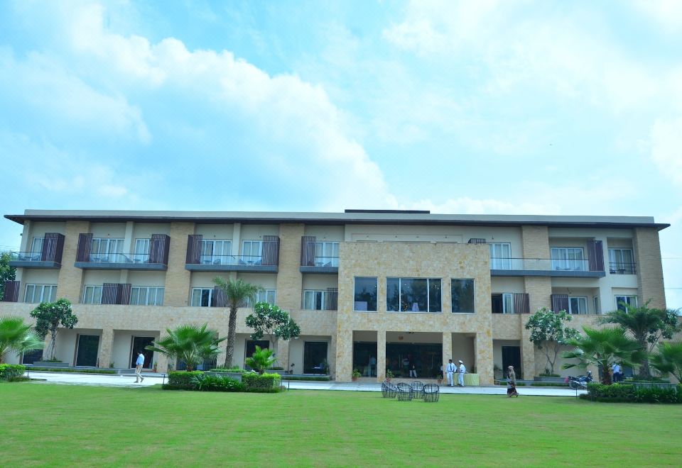 a large building with multiple floors and balconies is surrounded by a grassy area and palm trees at Ritz Resort