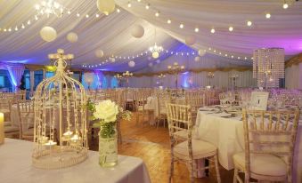 a beautifully decorated wedding reception with white tablecloths , chairs , and flowers , under a tent with lights at Hotel Doolin