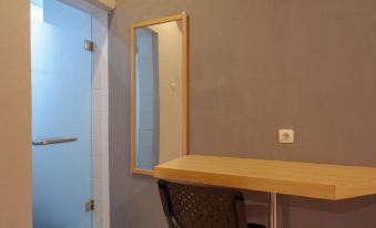 a small room with a wooden desk , a chair , and a mirror on the wall at RedDoorz Syariah @ Jalan Sultan Agung Tegal