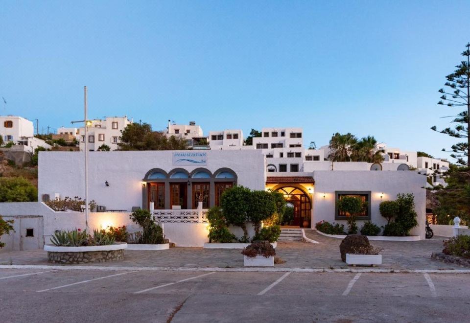 a large white house surrounded by grass and trees , with a car parked in front of it at Anamar Patmos