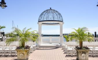 a white gazebo surrounded by potted plants and chairs on a wooden deck overlooking the ocean at Rod 'N' Reel Resort