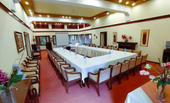 a large room with a long table surrounded by chairs and potted plants in the center at Lockwood Hotel Murree