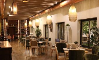 a dining room with wooden chairs and tables , along with potted plants and hanging light fixtures at Lantana Garden