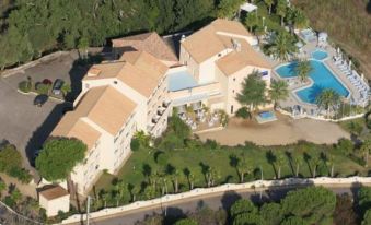 aerial view of a large building surrounded by trees and a pool , with a road in front of it at Hotel Corsica & Spa