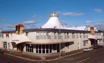 a large white building with a round roof and a sign on the corner of the building at The Lighthouse Hotel