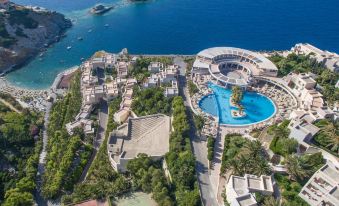 aerial view of a resort with a large pool surrounded by buildings and a tennis court at Athina Palace Resort & Spa