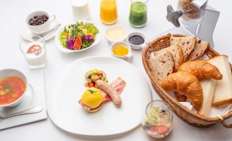a table is set with a variety of breakfast foods , including a plate of eggs , bacon , bread , and juice at Hotel la Alondra