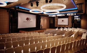 a large , empty conference room with rows of chairs and a podium , ready for an event at DoubleTree by Hilton Melaka