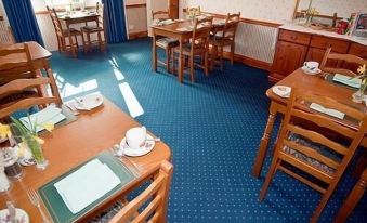 a dining room with wooden tables and chairs , blue carpet , and various items on the table at Linville River Log Cabins