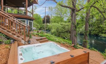 a wooden deck with a hot tub surrounded by trees , creating a serene and relaxing atmosphere at Stone Waters Inn