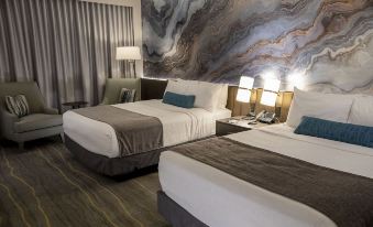 a hotel room with two beds , a large abstract painting on the wall , and lamps on both sides of the beds at Angel of the Winds Casino Resort