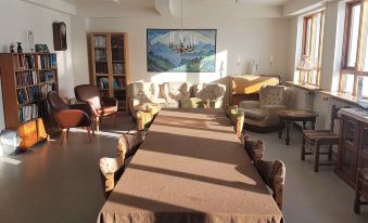 a long table with brown tablecloth and wooden chairs in a living room setting , along with a chandelier hanging from the ceiling at Holt Inn