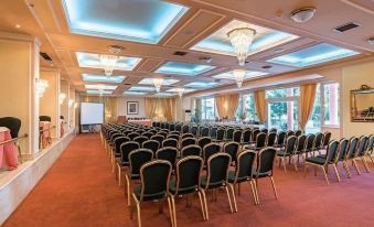 a large conference room filled with rows of chairs and a podium in the center , ready for an event or meeting at Hotel Philippos