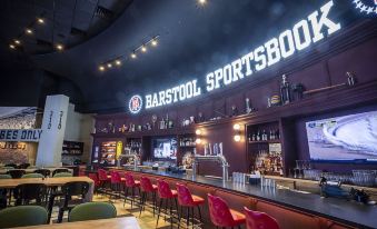 "a bar with a neon sign that says "" bar stool sportsbook "" in the background" at The Inn at Charles Town / Hollywood Casino