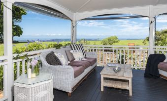 a cozy outdoor living area with a couch , table , and wicker furniture on a wooden deck overlooking a beautiful view of the ocean at Rosewood Estate
